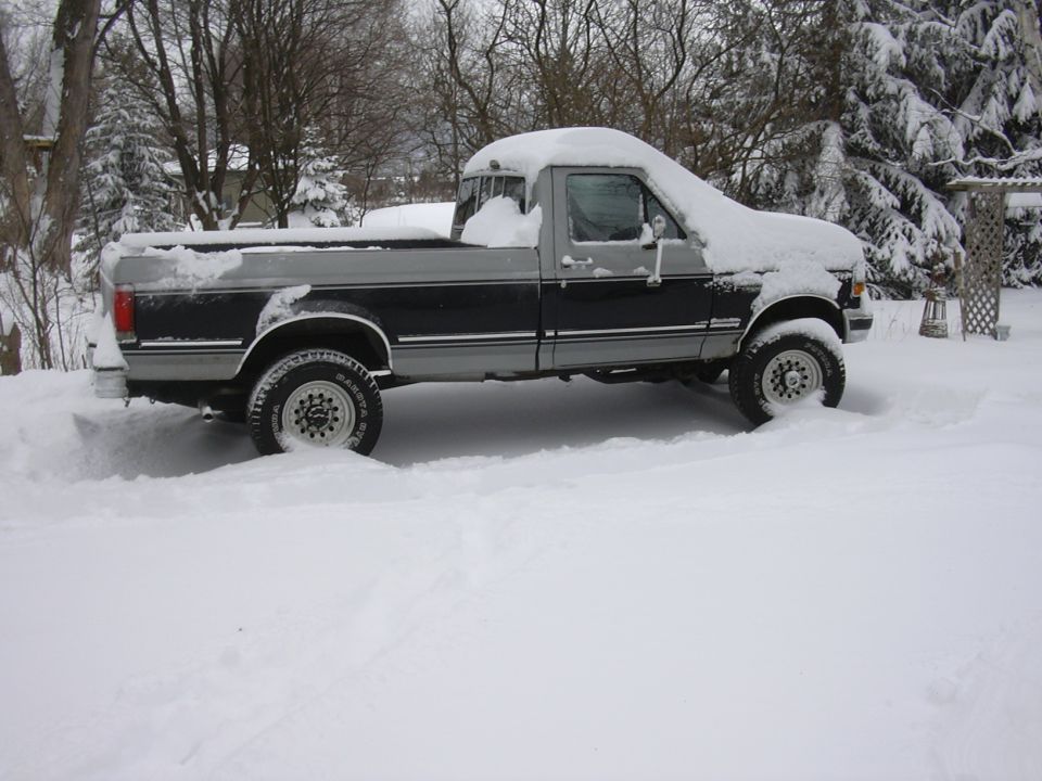 Pickup truck covered in snow, parked outside