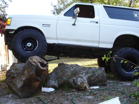 1989 Ford Bronco - White 1989 Ford Bronco with off-road tires is positioned over logs.