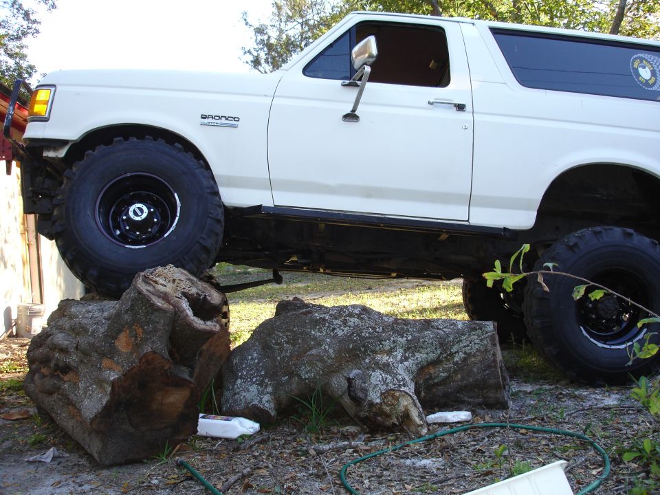 1989 Ford Bronco with large tires, partially obscured by logs