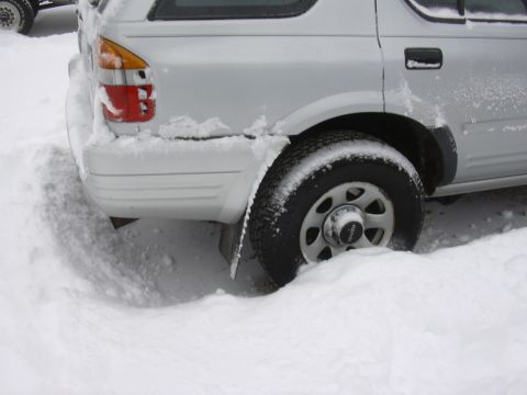 1996 Ford Crown Victoria - A silver SUV is stuck in deep snow, with only its rear visible.