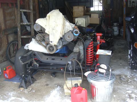 1996 Ford Crown Victoria - Various automotive parts, including an engine and chassis components, are stored in a cluttered garage setting.