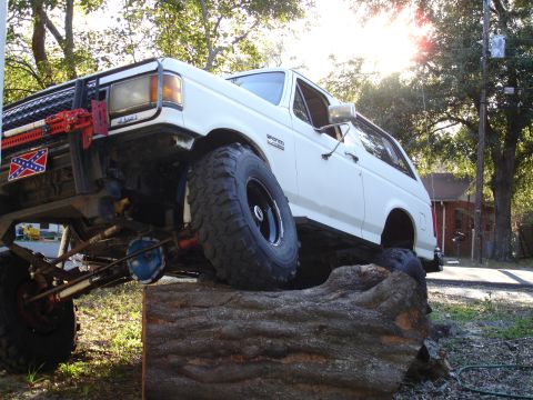 1989 Ford Bronco - A modified 1989 Ford Bronco is shown navigating an off-road obstacle made of a large log.