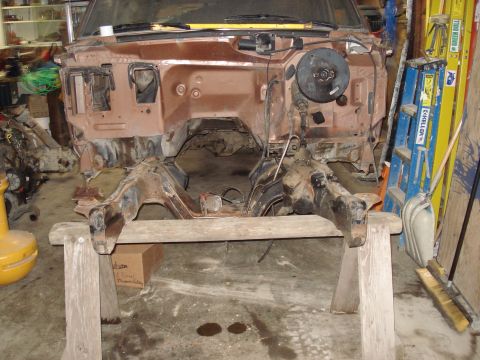 1989 Ford Bronco - Vehicle chassis and firewall disassembled and supported on sawhorses in a workshop.