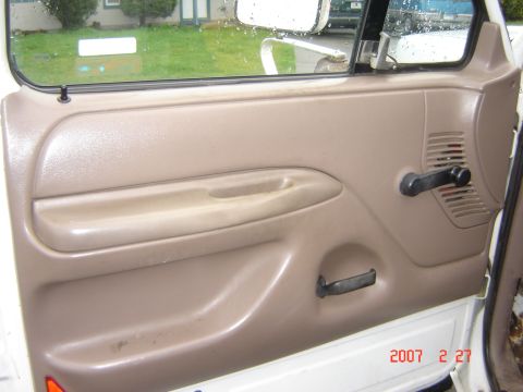 1993 Ford Bronco - Close-up of a vehicle's interior door panel, showing the armrest and manual window crank.