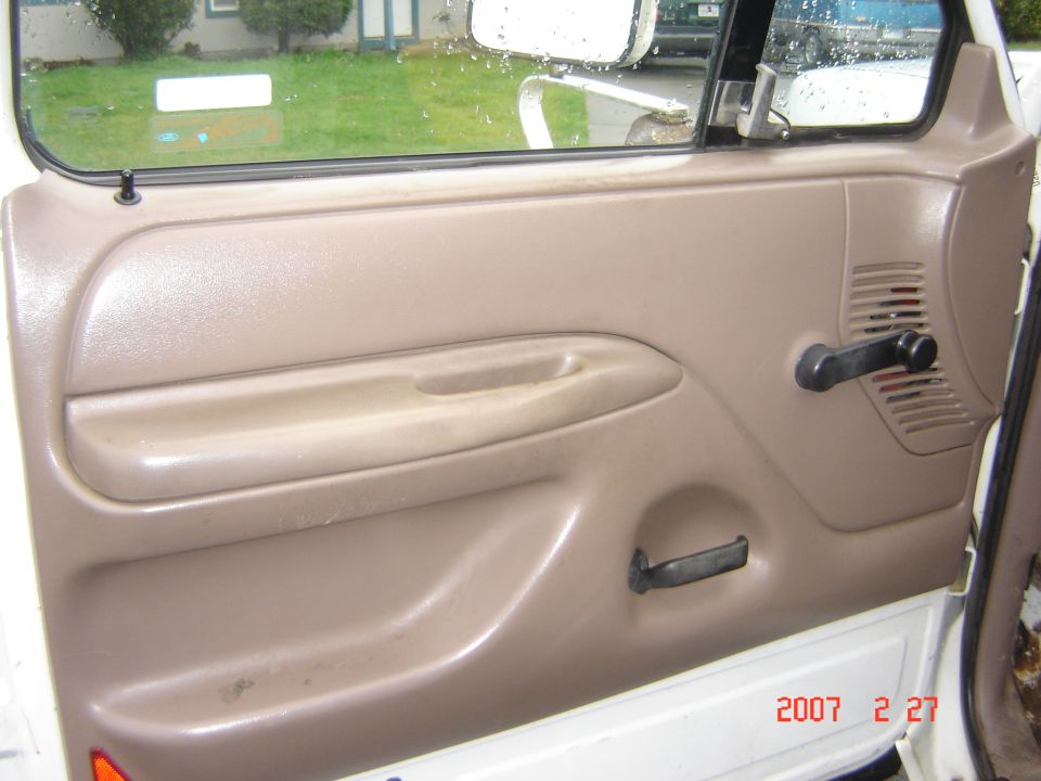 Tan door panel with manual window crank inside a white truck door