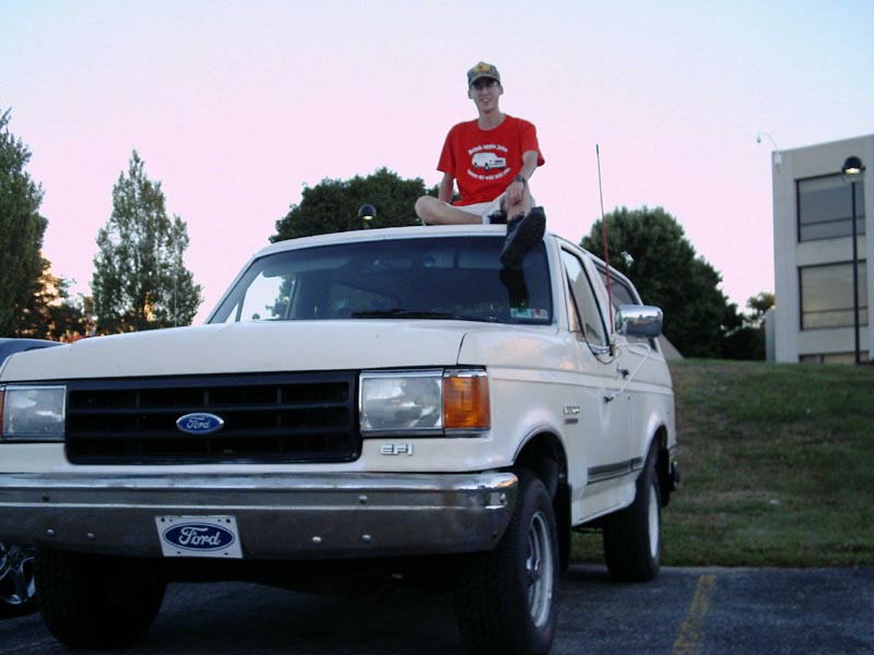 White 1988 Ford Bronco with person on roof