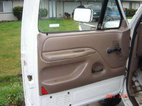 1993 Ford Bronco - Interior view of a truck door panel with tan trim and black hardware, seen from the exterior.