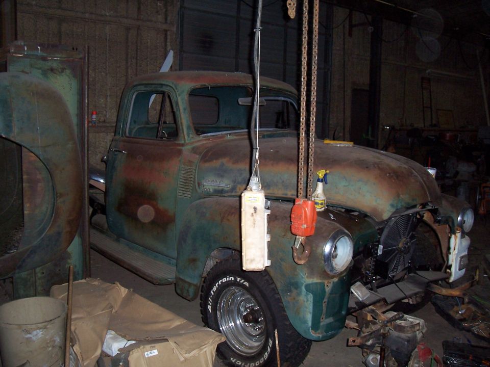 Rusty green pickup truck in a garage, front quarter view