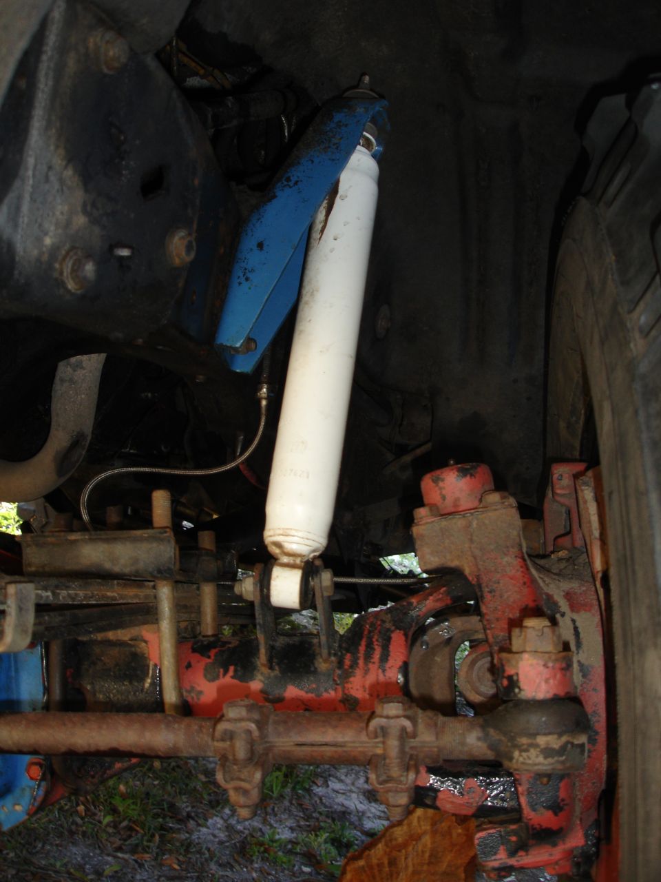 Close-up of vehicle suspension with white shock absorber and blue bracket