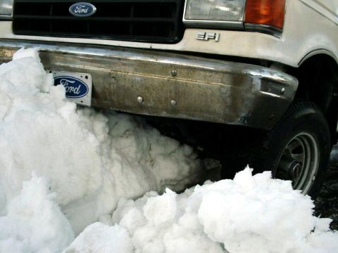 1988 Ford Bronco - A Ford truck's front bumper is buried in snow, obscuring most of the vehicle.