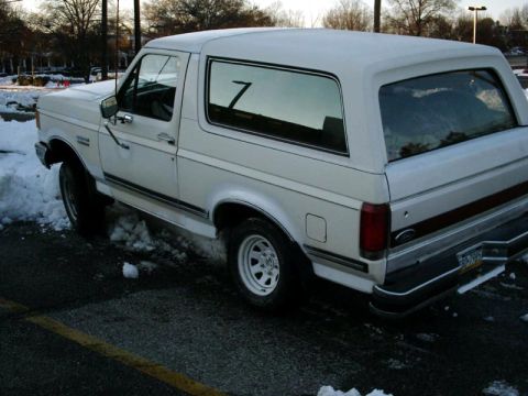1988 Ford Bronco - A white 1988 Ford Bronco is seen parked in a snowy lot, viewed from the front three-quarter angle.