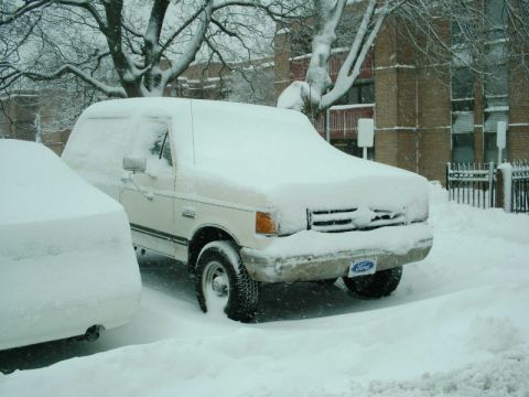 1988 Ford Bronco - A 1988 Ford Bronco is parked and covered in snow during a winter storm.