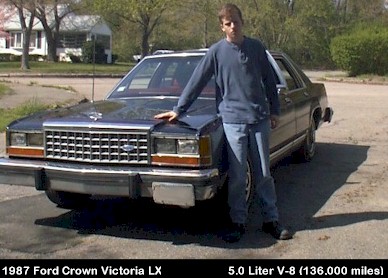 1987 Ford Crown Victoria LTD - A man stands by a 1987 Ford Crown Victoria LX, its front grille and headlights.