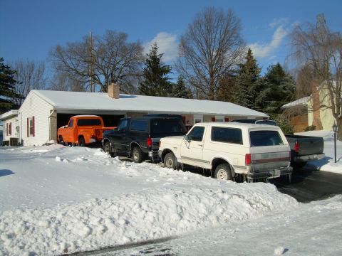 1988 Ford Bronco - Multiple vehicles are parked in the snow, including a white SUV with icicles hanging from its rear bumper.