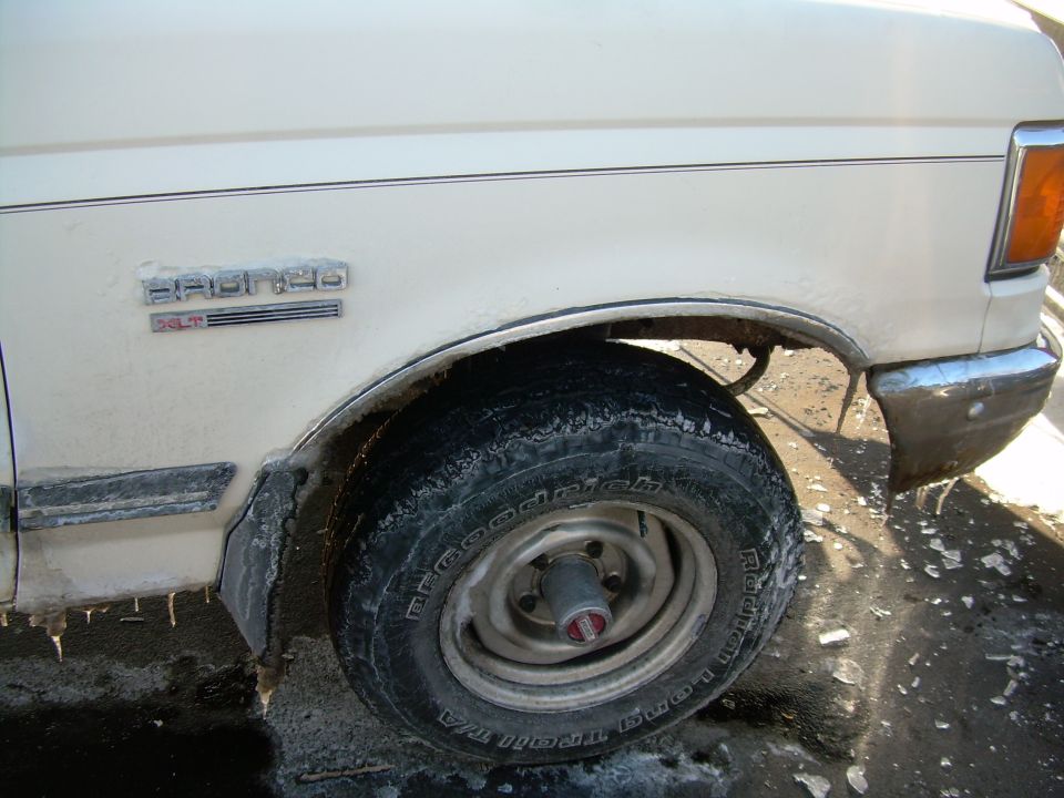 White Ford Bronco XLT side view, showing front wheel and fender. Some snow on the vehicle