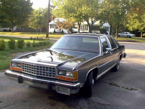 1987 Ford Crown Victoria LTD - A 1987 Ford Crown Victoria LTD sedan is seen from the front three-quarter angle on a sunny day.