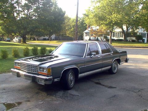 1987 Ford Crown Victoria LTD - This 1987 Ford Crown Victoria LTD sedan is seen with its hood open, parked on a paved surface.