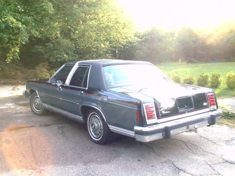 1987 Ford Crown Victoria LTD - The rear of a 1987 Ford Crown Victoria LTD sedan is shown parked outdoors.