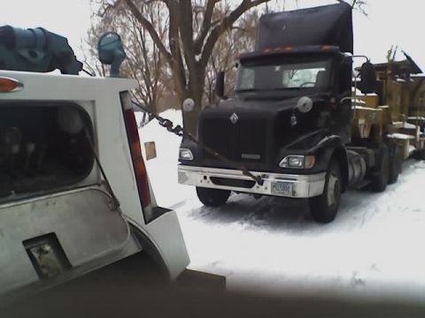 1992 Ford Bronco - A tow truck is seen towing a black semi-truck through a snowy landscape.