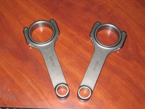 1991 Ford Bronco - A pair of connecting rods are shown, each stamped with "6300.BS" and resting on a wood-grain background.