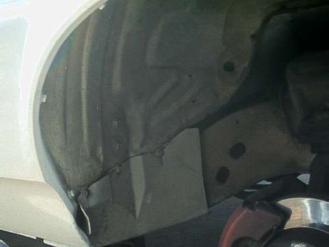 1976 Ford Ranchero - Close-up view of the interior of a vehicle's wheel well, revealing the inner fender liner and suspension parts.