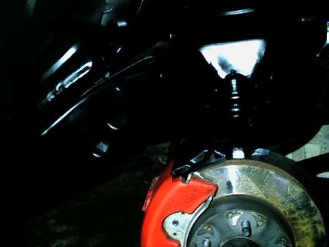 1976 Ford Ranchero - Close-up view of a vehicle's front brake assembly, a red caliper and a vented rotor.