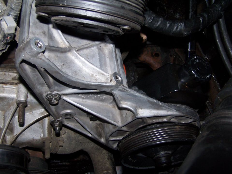 Close-up of engine bracket with multiple pulleys and hoses