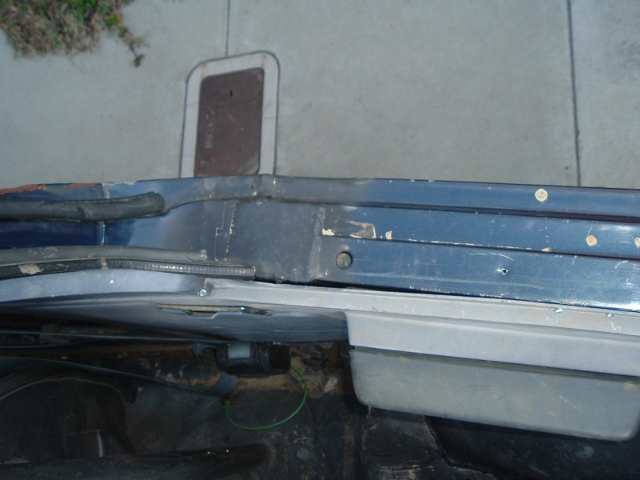 Close-up of vehicle body seam and rocker panel with bare metal repair marks