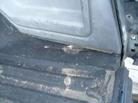 1989 Ford Bronco - Close-up of a vehicle's interior door panel and floor, showing dirt and wear.