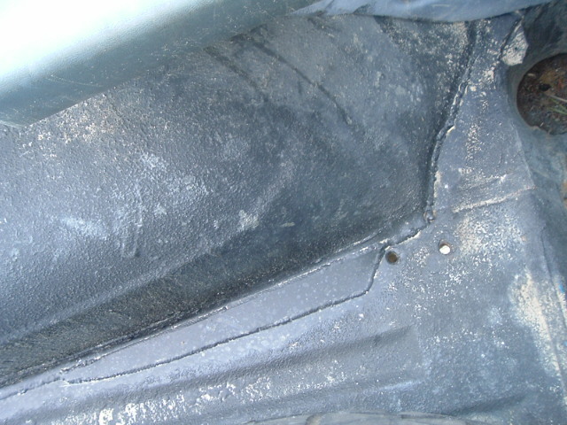 Close-up of a wheel well and rocker panel coated in textured black undercoating