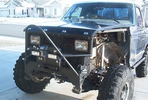 1986 Ford Bronco - This modified Ford truck features a custom bumper and grille, with its engine partially exposed.