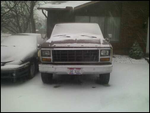 Snow-covered red Ford pickup, front view, with Ohio plate in a snowy driveway