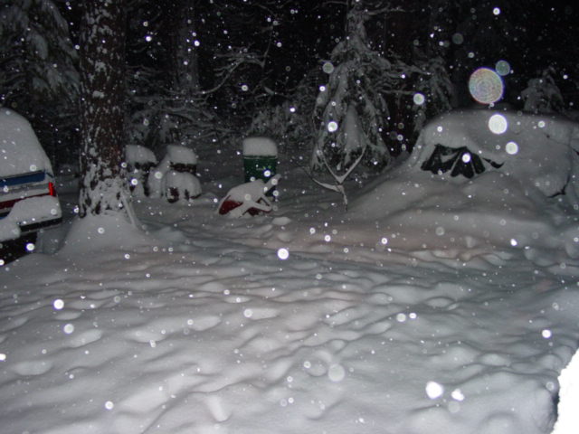 snow falling on a campsite with a car and a tent covered in snow