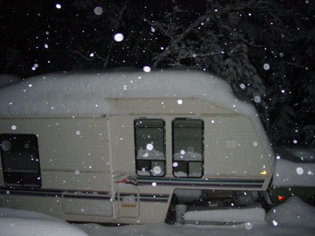 Camper trailer covered in snow at night