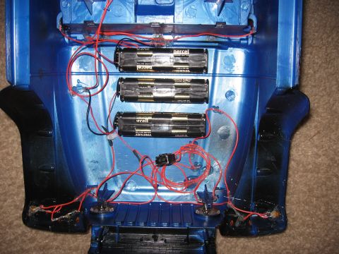 1990 Ford Bronco - Inside view of a blue RC truck body shell showing a scratch-built lighting harness: three hot-glued AA battery holders loaded with Duracell…