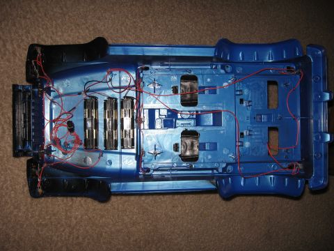 1990 Ford Bronco - The underside of a blue toy truck reveals its internal wiring and battery compartments.