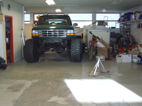 1996 Ford Bronco - A lifted 1996 Ford Bronco with massive tires sits in a cluttered garage.