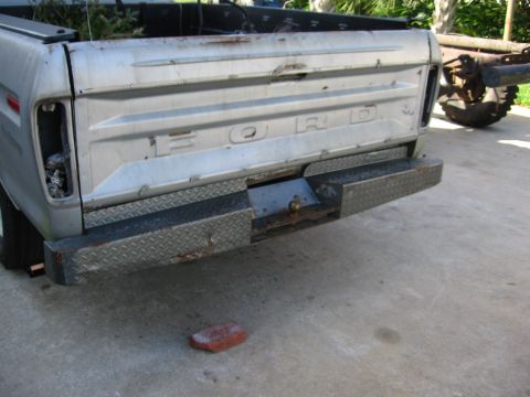 1974 Ford F-100 - Rear view of a silver Ford truck, showing the tailgate and diamond plate bumper. Tail light is missing.