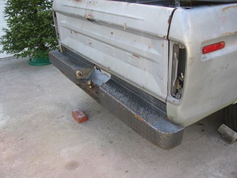 1974 Ford F-100 - Rear view of a silver pickup truck a diamond plate bumper and a missing taillight assembly. The body style suggests a 1974 Ford F-100.