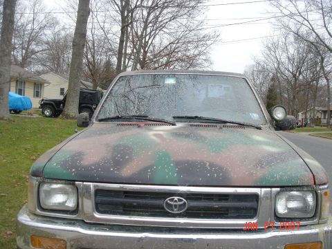 1992 Toyota Tacoma - A Toyota pickup truck with a camouflage paint job is parked on a residential street.