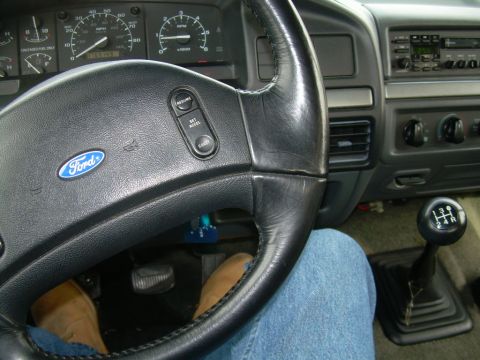 1992 Ford Bronco - The interior of a 1992 Ford Bronco, showing the steering wheel, dashboard, and manual transmission shifter.