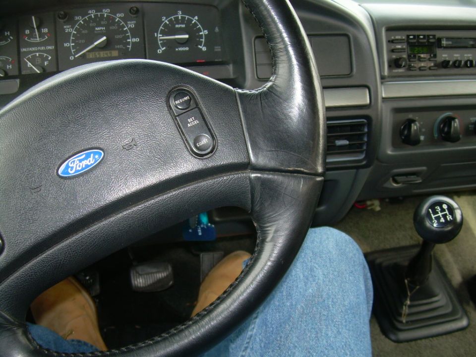 Ford truck interior showing steering wheel, gauge cluster, dash radio and 5-speed manual shifter