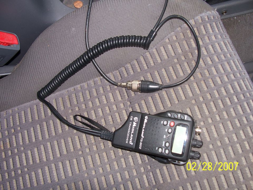 Midland 75-822 handheld CB radio with coiled cable on gray vehicle seat