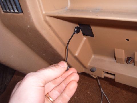 1988 Ford Bronco - Close-up of a hand holding a glove box latch pull inside a vehicle's interior.