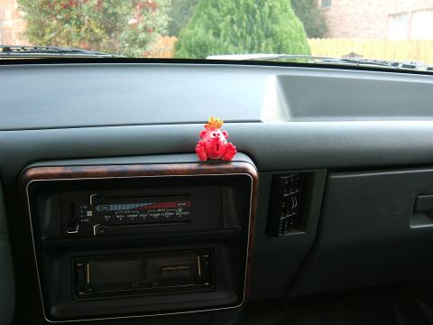 1991 Ford Bronco - A small red toy sits atop the dashboard of a vehicle, near the climate controls.