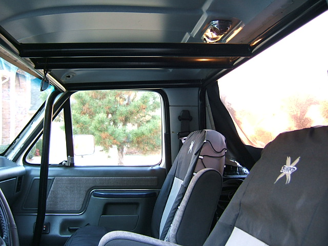 1991 Ford Bronco interior showing roll cage, seats with covers, and door panel