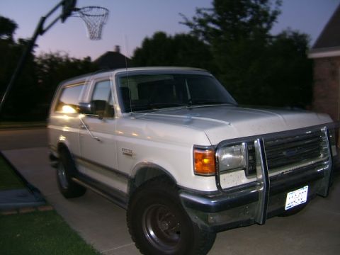 1991 Ford Bronco - White 1991 Ford Bronco with a chrome brush guard is parked in a driveway at dusk.
