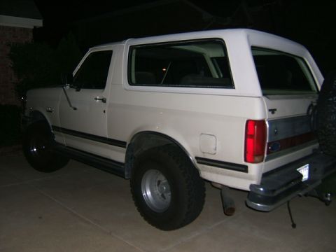 1991 Ford Bronco - Rear quarter view of a white 1991 Ford Bronco parked on a paved surface at night.
