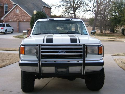 1991 Ford Bronco - Front view of a white 1991 Ford Bronco with black racing stripes on the hood and a chrome grille guard.