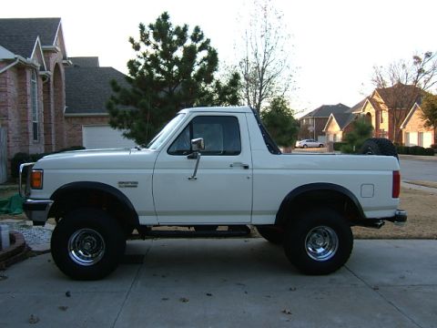 1991 Ford Bronco - This lifted Ford Bronco is parked in a suburban driveway with houses in the background.